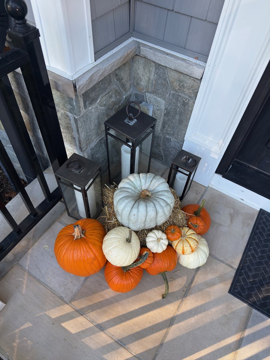 Blue-gray heirloom and white pumpkins tucked between porch lanterns