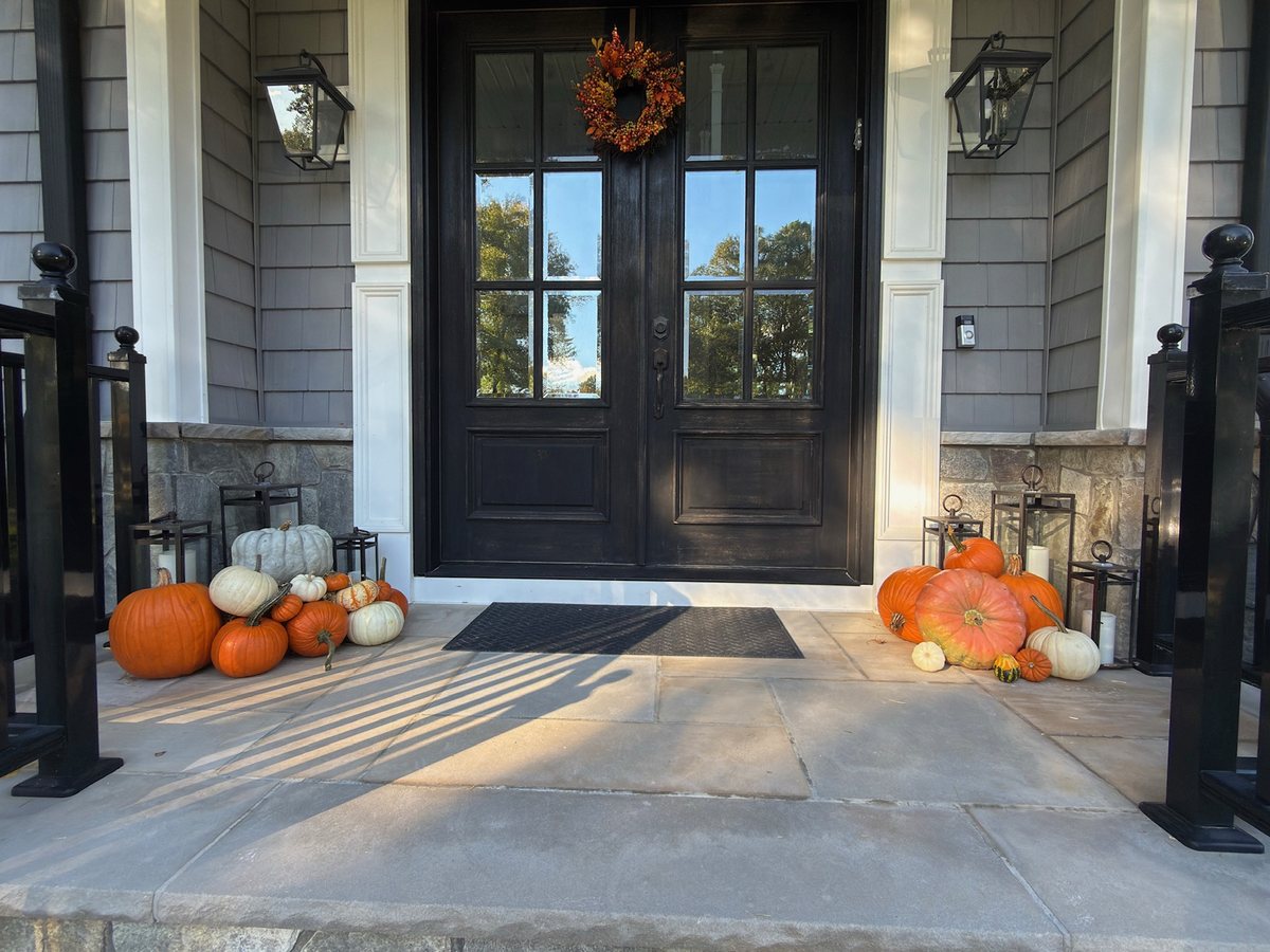Pumpkin porch display framing black double front doors with lanterns in Bergen County, NJ