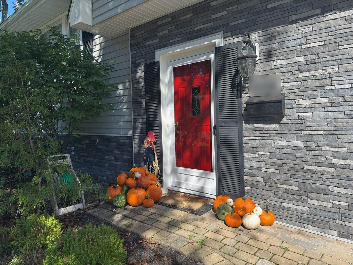 Orange and white pumpkin porch display around a red front door