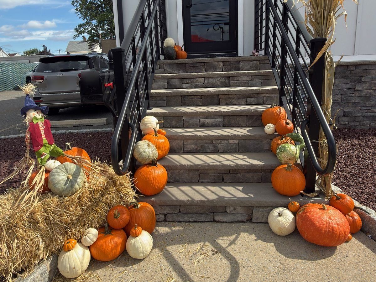 Storefront fall decorating at a Hackensack, NJ office entrance: pumpkins and a scarecrow